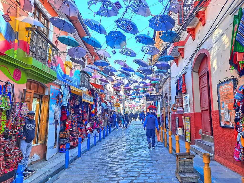 Colorful street lined with shops and umbrellas.